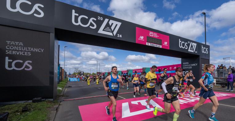 Multiple people running over the start line of the TCS London Marathon