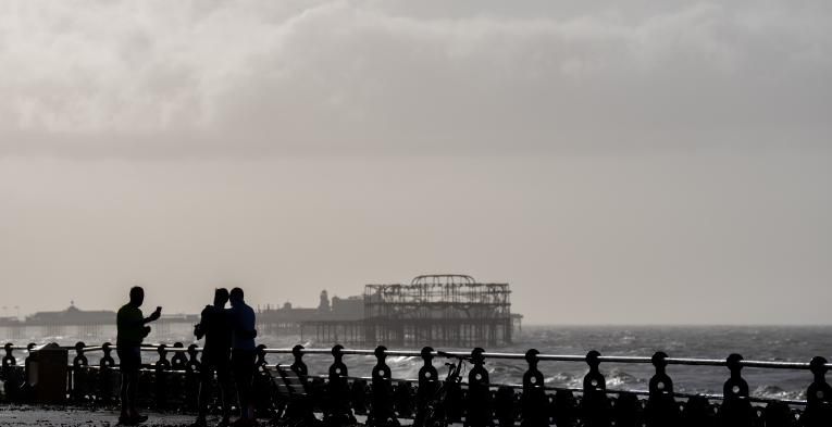 View of the Brighton pier with people silhouetted  in the foreground