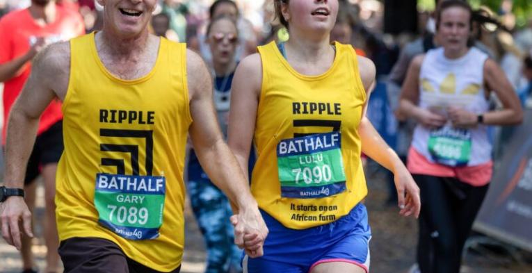 Two runners wearing yellow vests holding hands.