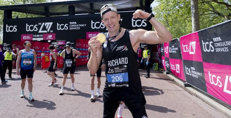 Richard Whitehead posing with his medal at the Finish Line