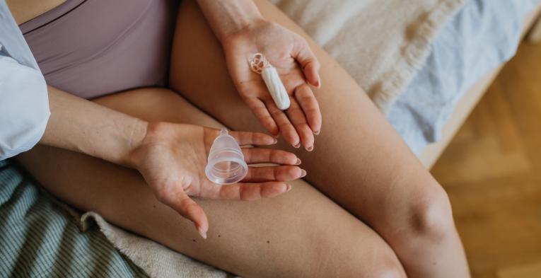 Woman holding a mooncup and tampon in her hands