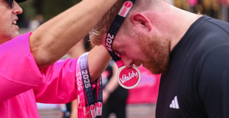 Volunteer puts a medal on a runner