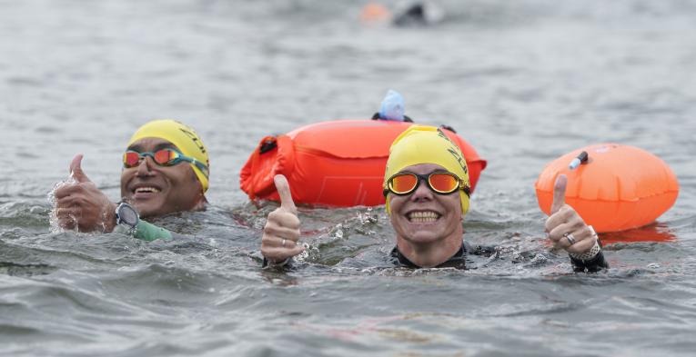 Swimmers give a thumbs up in the water