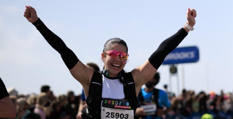A runner punches their hands in the air close to the Finish Line