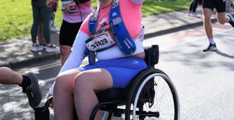 Wheelchair uses poses for the camera on the course