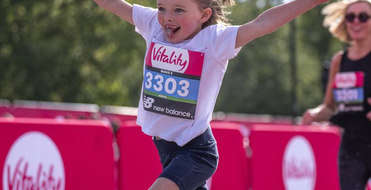 Vitality Westminster Mile runner throws their arms in the air