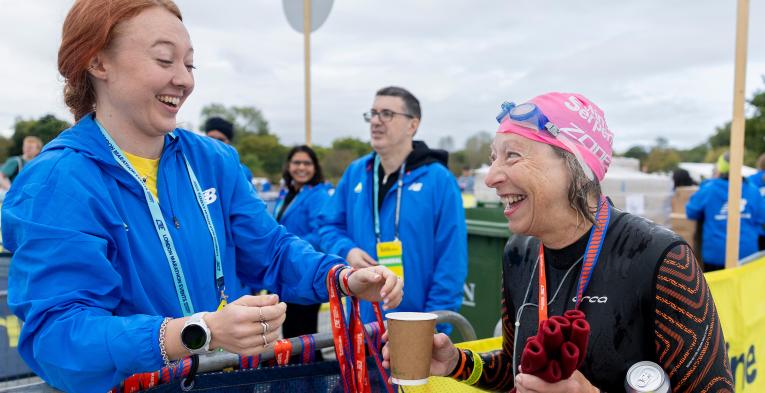 Volunteer hands out a medal at 2026 Swim Serpentine