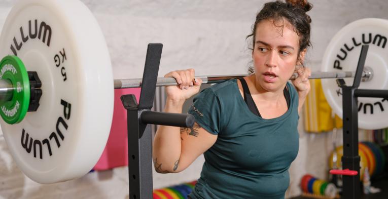A female weight lifter racking a bar in a gym