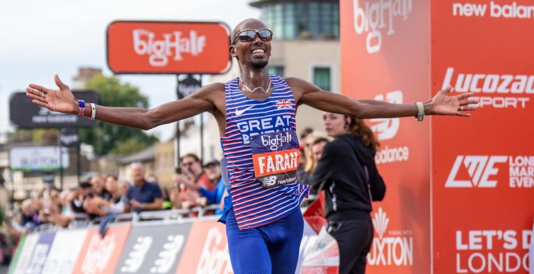 Sir Mo Farah crosses the finish line in front of the Cutty Sark at the 2022 Big Half