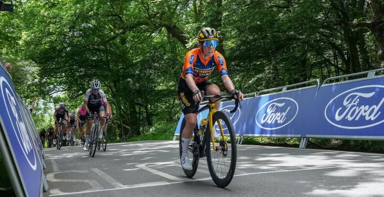 Elite cyclists ride past Ford branding