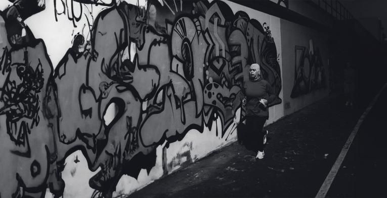 Local runner, Ruba Talukdar running. through an urban alley with graffiti on the walls