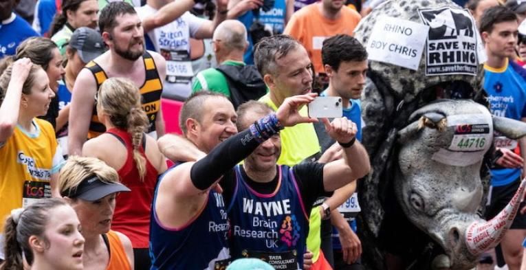 Photo of participants at the TCSLM 2023, including someone dressed as a Rhino and two men taking a selfie
