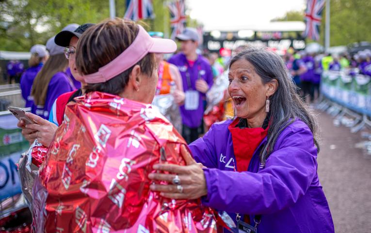 Volunteer congratulates a finisher at the end of the TCS London Marathon