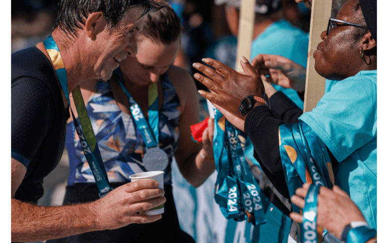 A volunteer hands a participant his medal