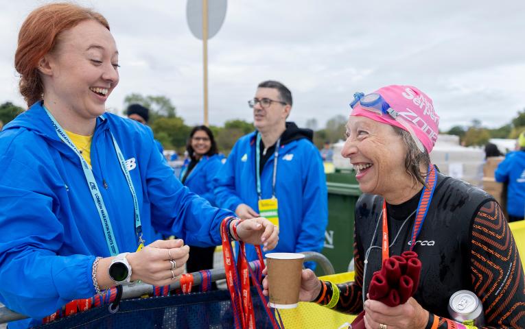 Volunteer hands out a medal at 2026 Swim Serpentine