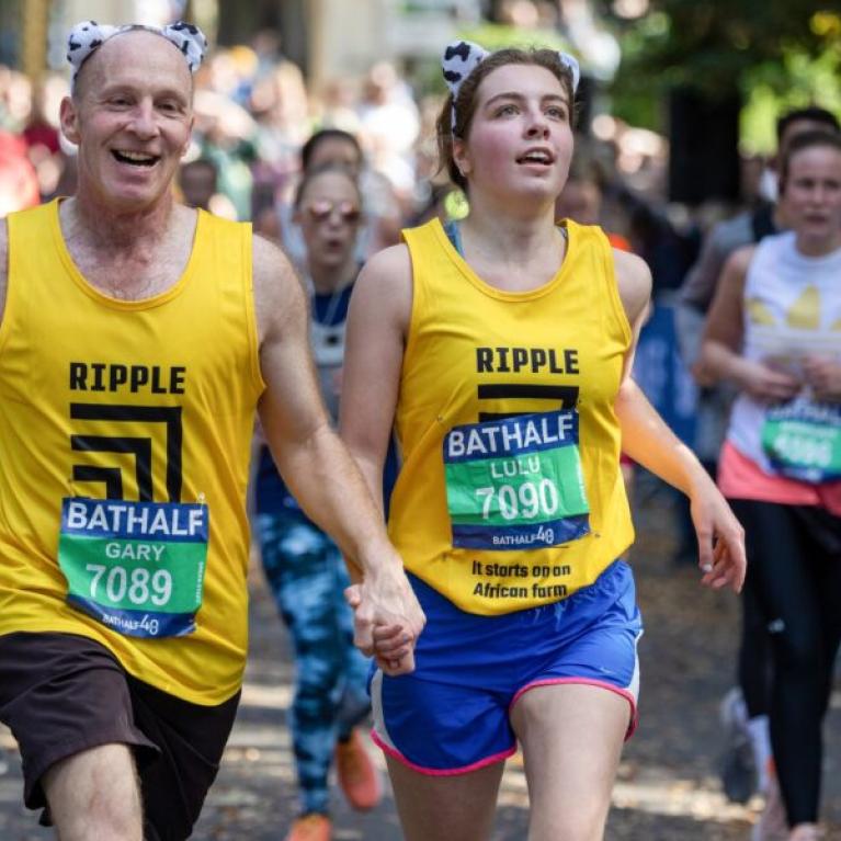 Two runners wearing yellow vests holding hands.