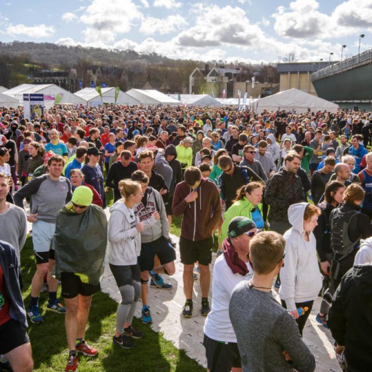 A crowd of people standing on a field next to the rugby stadium in Bath.