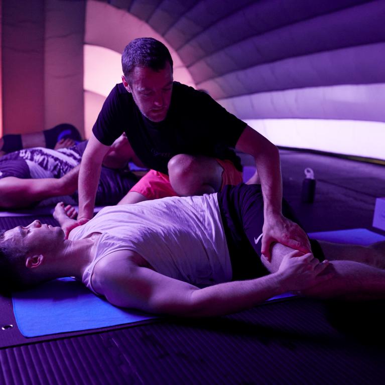 Colly adjusts someone in a class at Hotpod Yoga