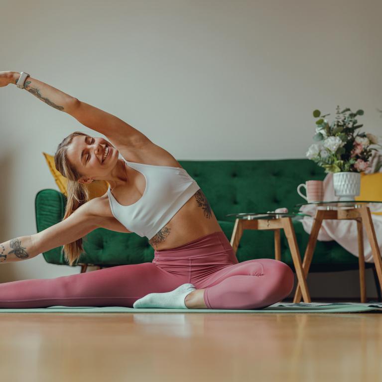 A woman stretches out on a yoga mat in her house