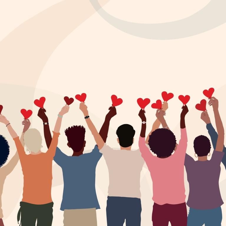Crowd of people from behind holding up hearts 