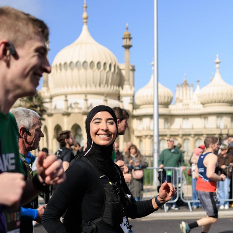 Runner smiles at the camera while passing the Royal Pavilion