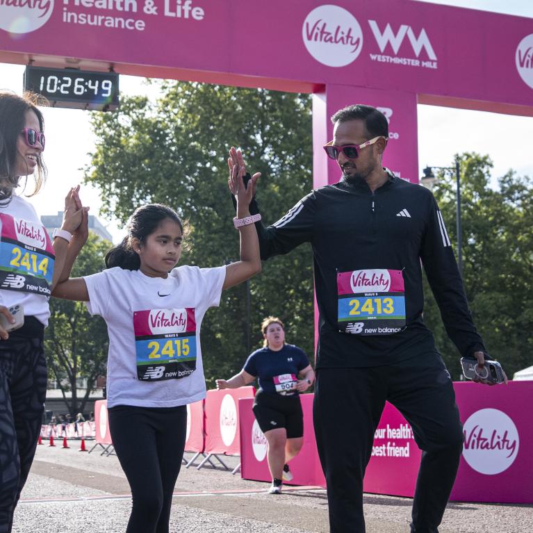 A family high five at the Vitality Westminster Mile Finish Line