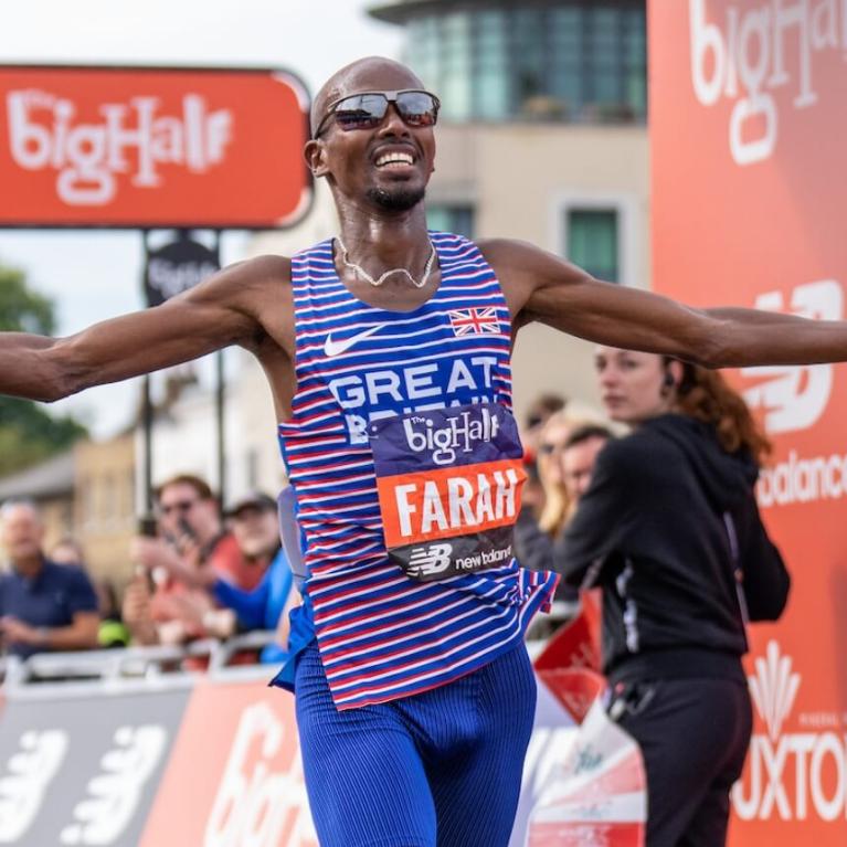 Sir Mo Farah crosses the finish line in front of the Cutty Sark at the 2022 Big Half