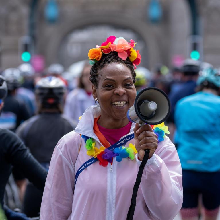 A smiling volunteer with a megaphone on Tower Bridge during RideLondon