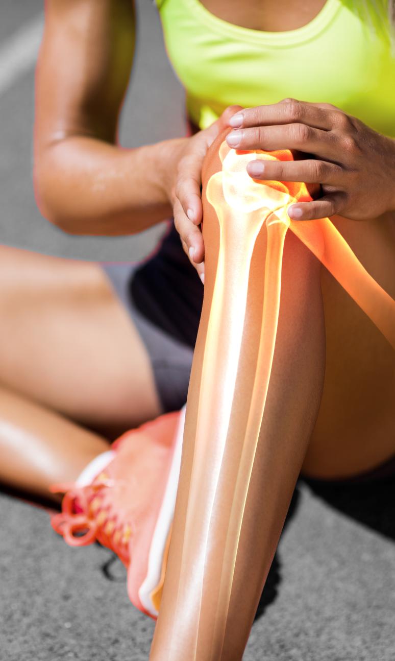 Runner suffering from knee pain while sitting on track during a sunny day