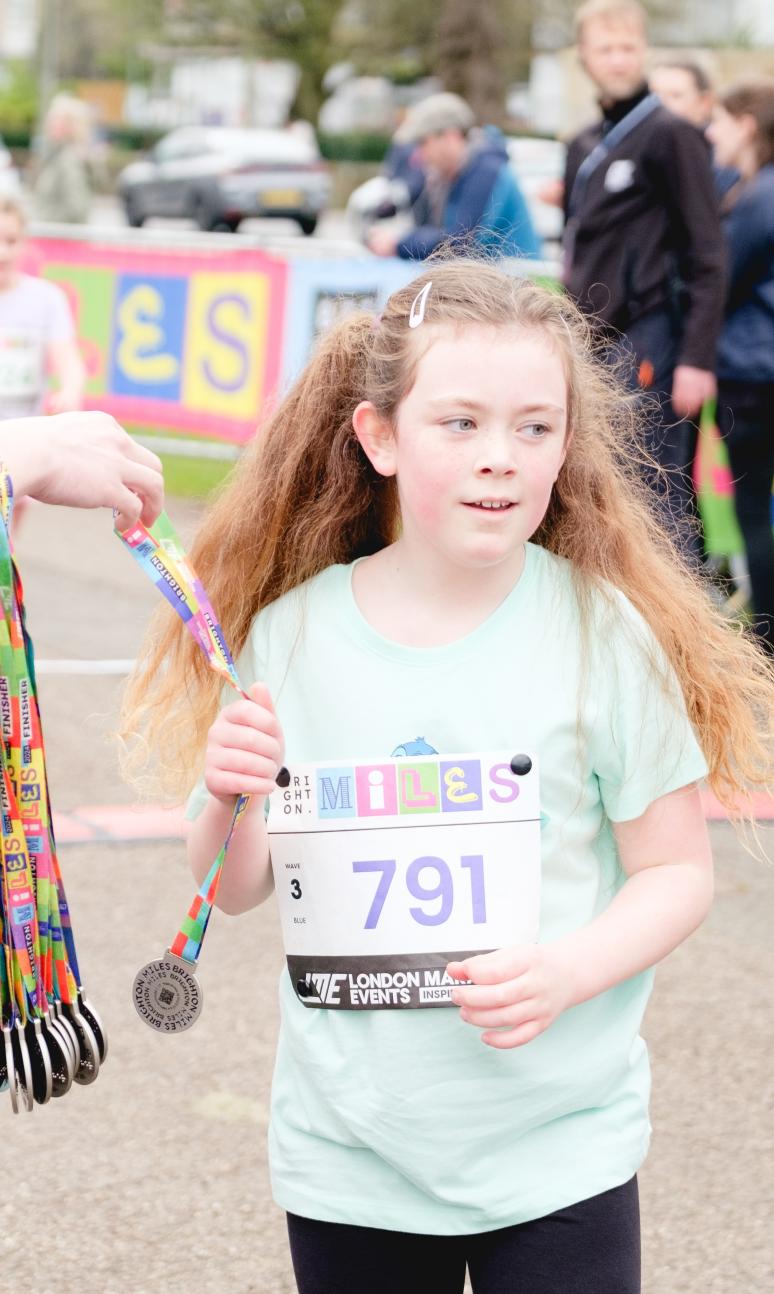 Brighton Miles finisher collecting their medal 
