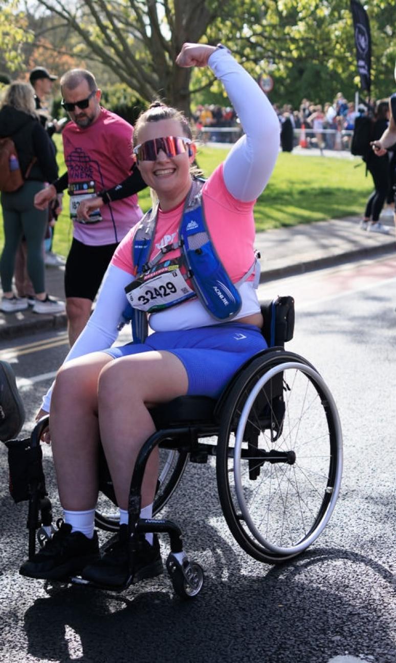 Wheelchair uses poses for the camera on the course