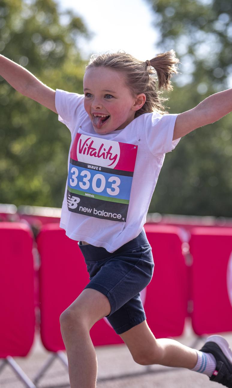 Vitality Westminster Mile runner throws their arms in the air