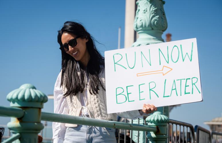 Spectator with a run now beer later sign