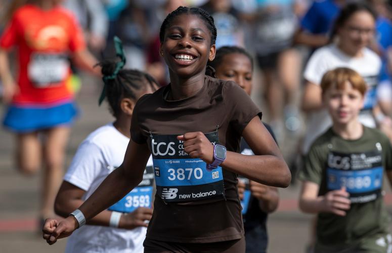 A smiling participant completes the TCS Mini London Marathon 