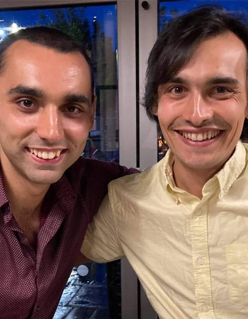 Two brother sat next to each other with their arm on each others shoulders 