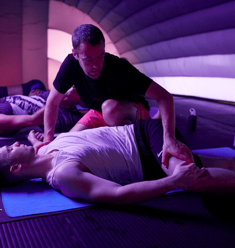 Colly adjusts someone in a class at Hotpod Yoga