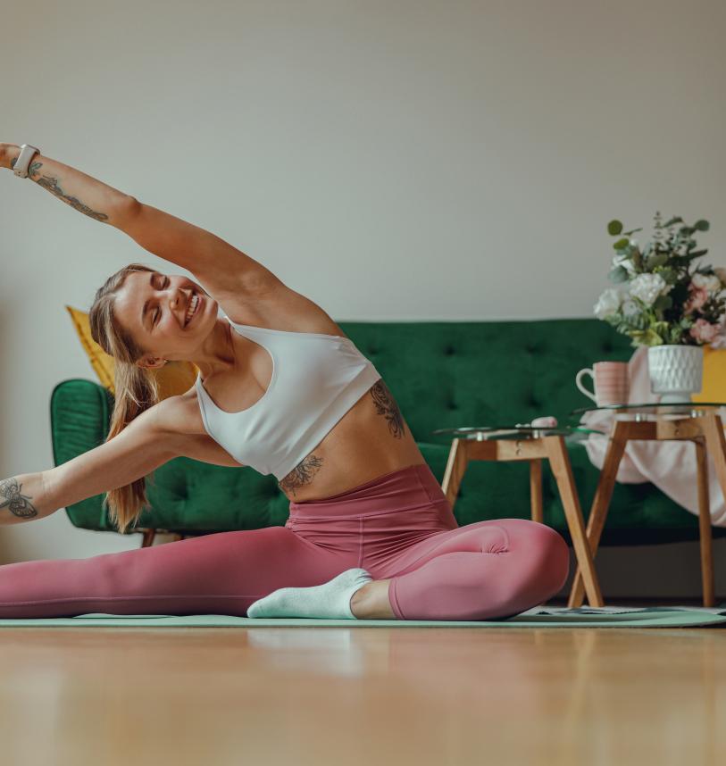 A woman stretches out on a yoga mat in her house