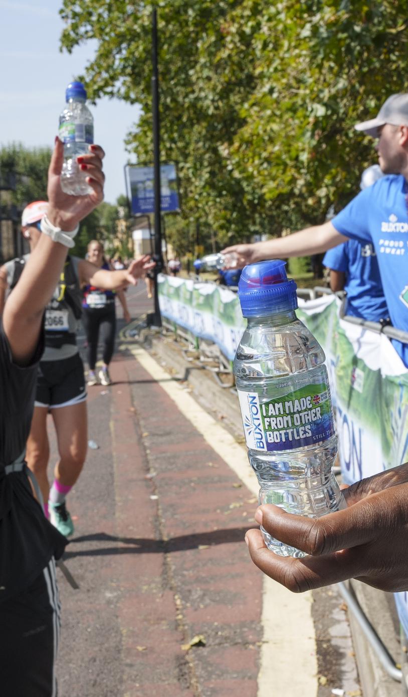 Volunteers hold out bottles of water to runners 