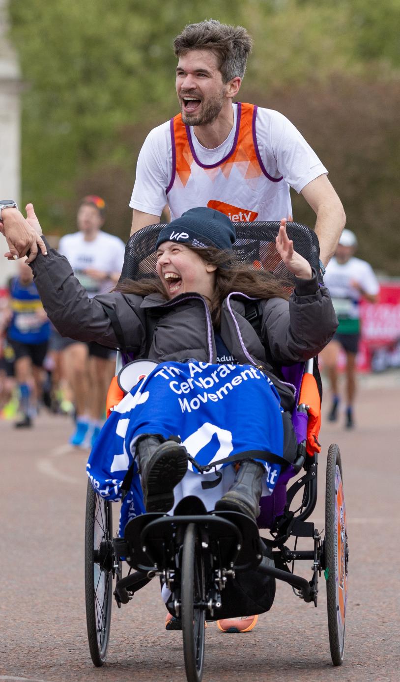 Man pushing women in a wheelchair with another women holding the hand of the women in the wheelchair.