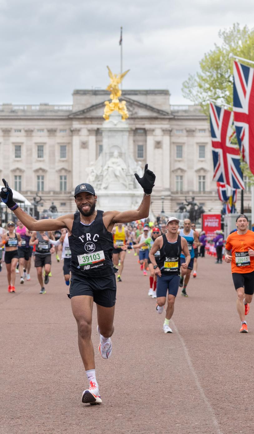 Person approaching the finish line with arms in the air. Multiple runners behind them.