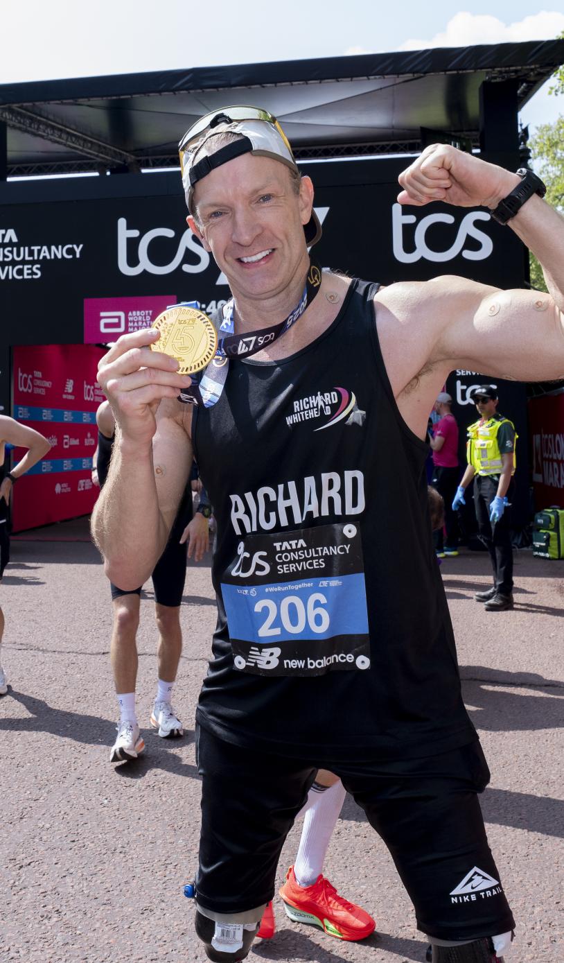 Richard Whitehead posing with his medal at the Finish Line