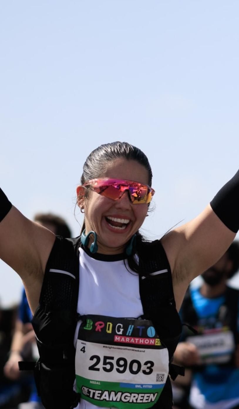 A runner punches their hands in the air close to the Finish Line
