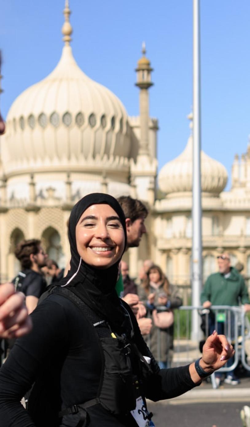 Runner smiles at the camera while passing the Royal Pavilion