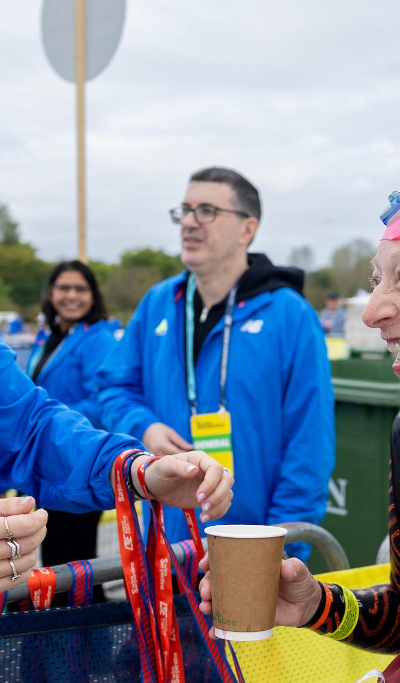 Volunteer hands out a medal at 2026 Swim Serpentine
