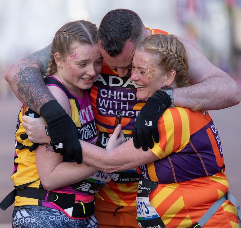 A group of runners hug on the finish line of the London Marathon