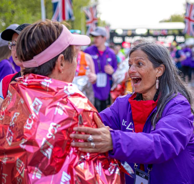 Volunteer congratulates a finisher at the end of the TCS London Marathon