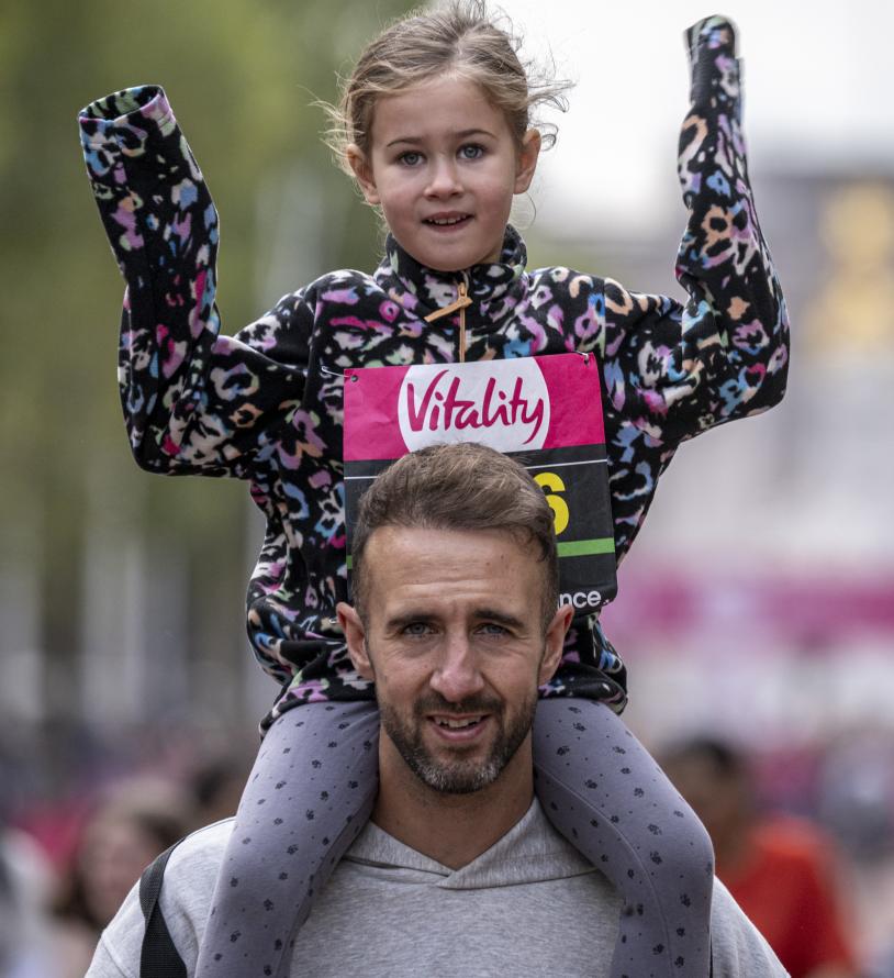 An adult carries a child on their shoulders 